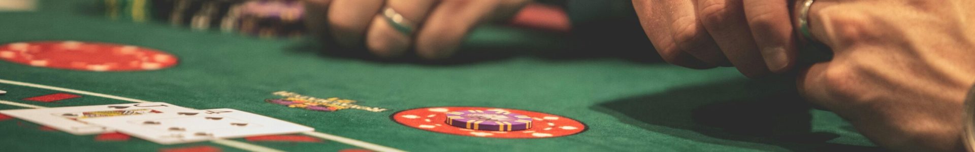 pexels-photo-1871508-1871508-1 Hands playing blackjack in a casino setting with cards and chips on a green table.